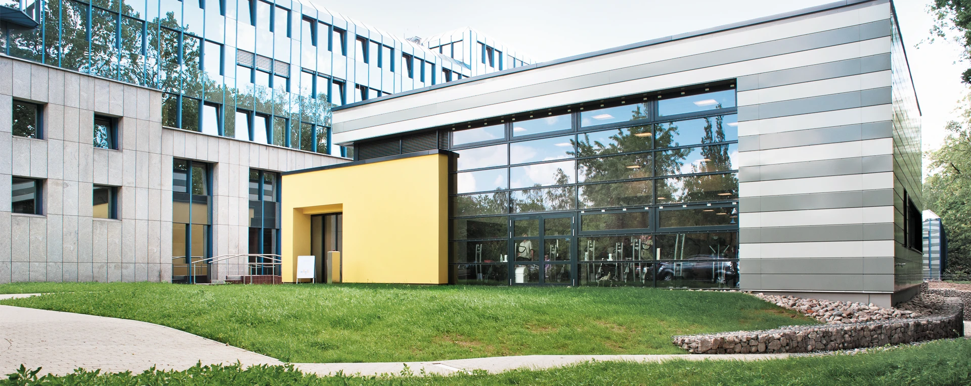 DianaMedicalSport | Ansicht des lichtdurchfluteten Gebäudes Außenansicht des DianaMedicalSport-Gebäudes mit großer Glasfassade und gelbem Eingangsbereich